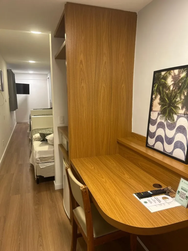 Escrivaninha de madeira com quadro de Copacabana na Suíte Cápsula tripla