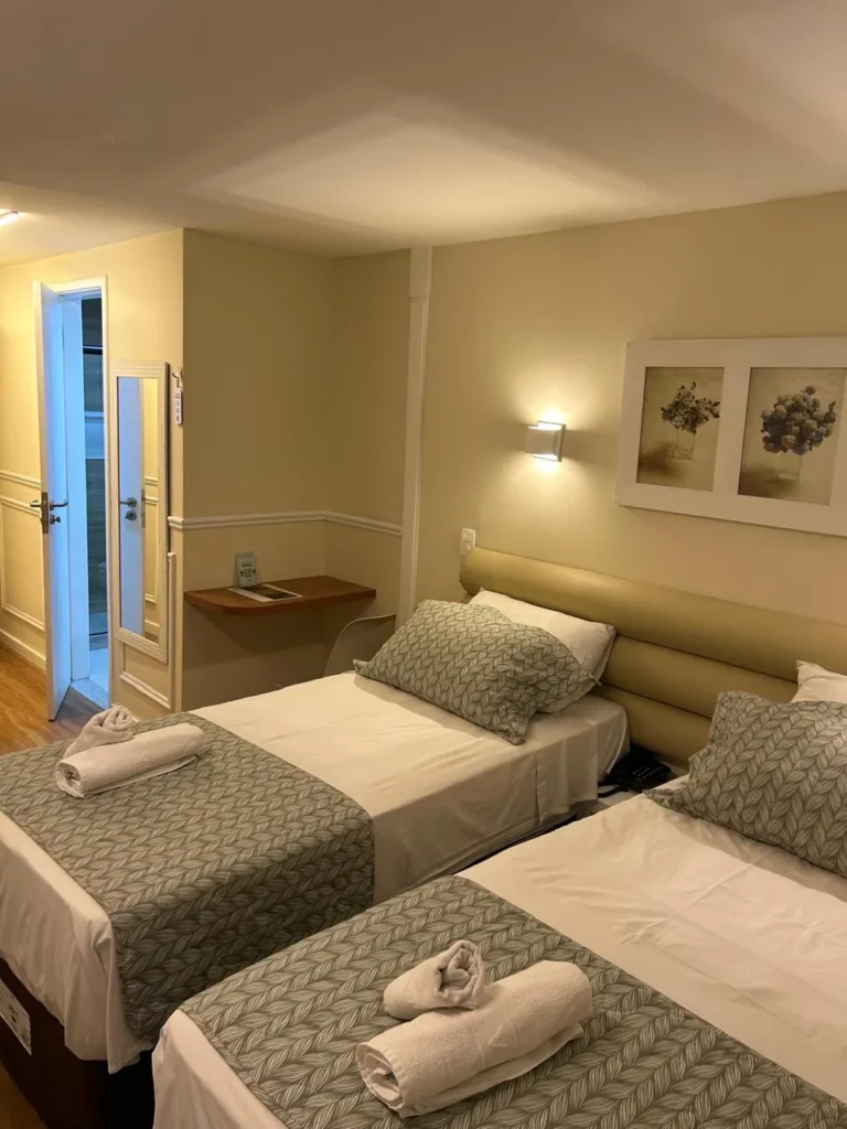 Quarto twin com cabeceira estofada, duas camas de solteiro e quadros de flores