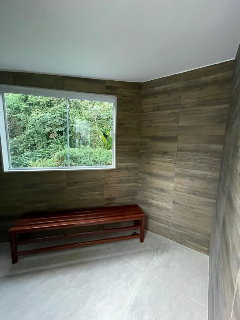 Sauna a vapor com banco de madeira e janela para a vegetação