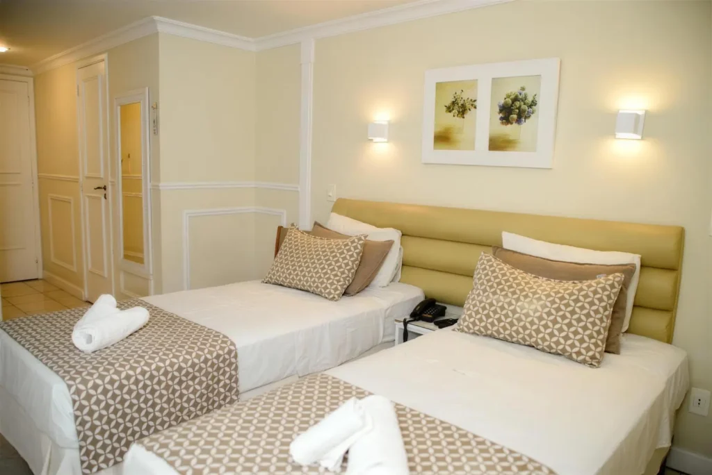 Quarto Standard Twin claro com duas camas de solteiro e toalhas dobradas em forma de cisne