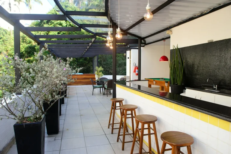 Área gourmet da cobertura com balcão preto e amarelo e banquetas de madeira